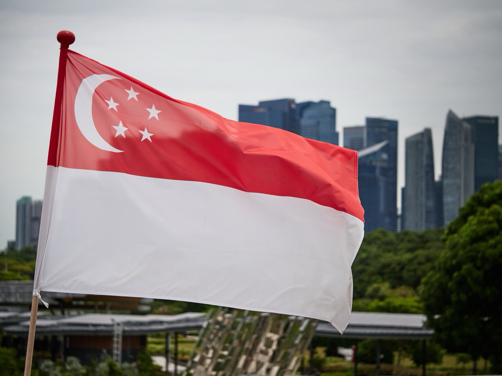 The Singapore flag flying, with the city skyline behind it